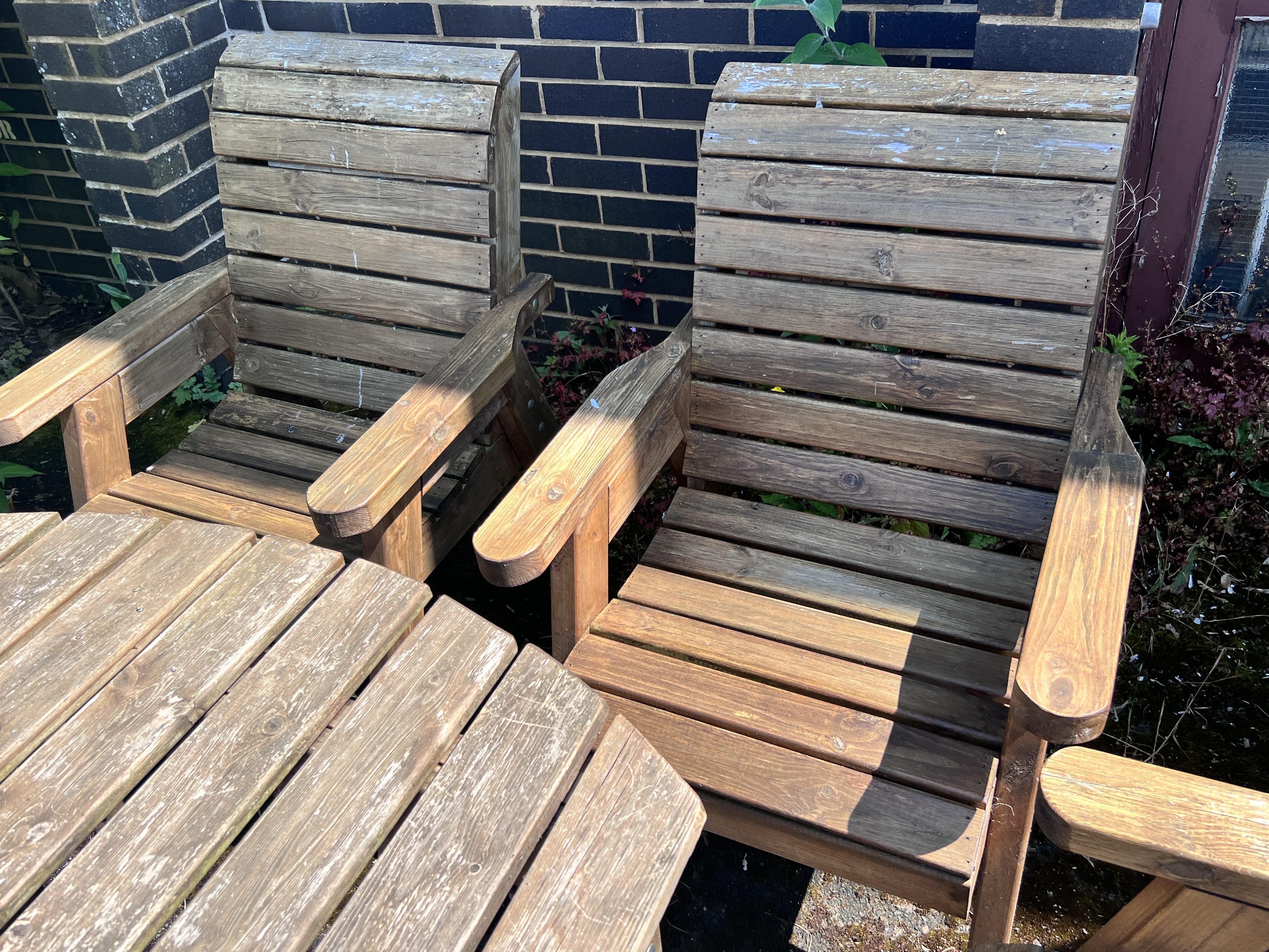 A rectangular slatted teak garden table, length 130cm, width 96cm, height 79cm, together with a pair of armchairs and a pair of benches